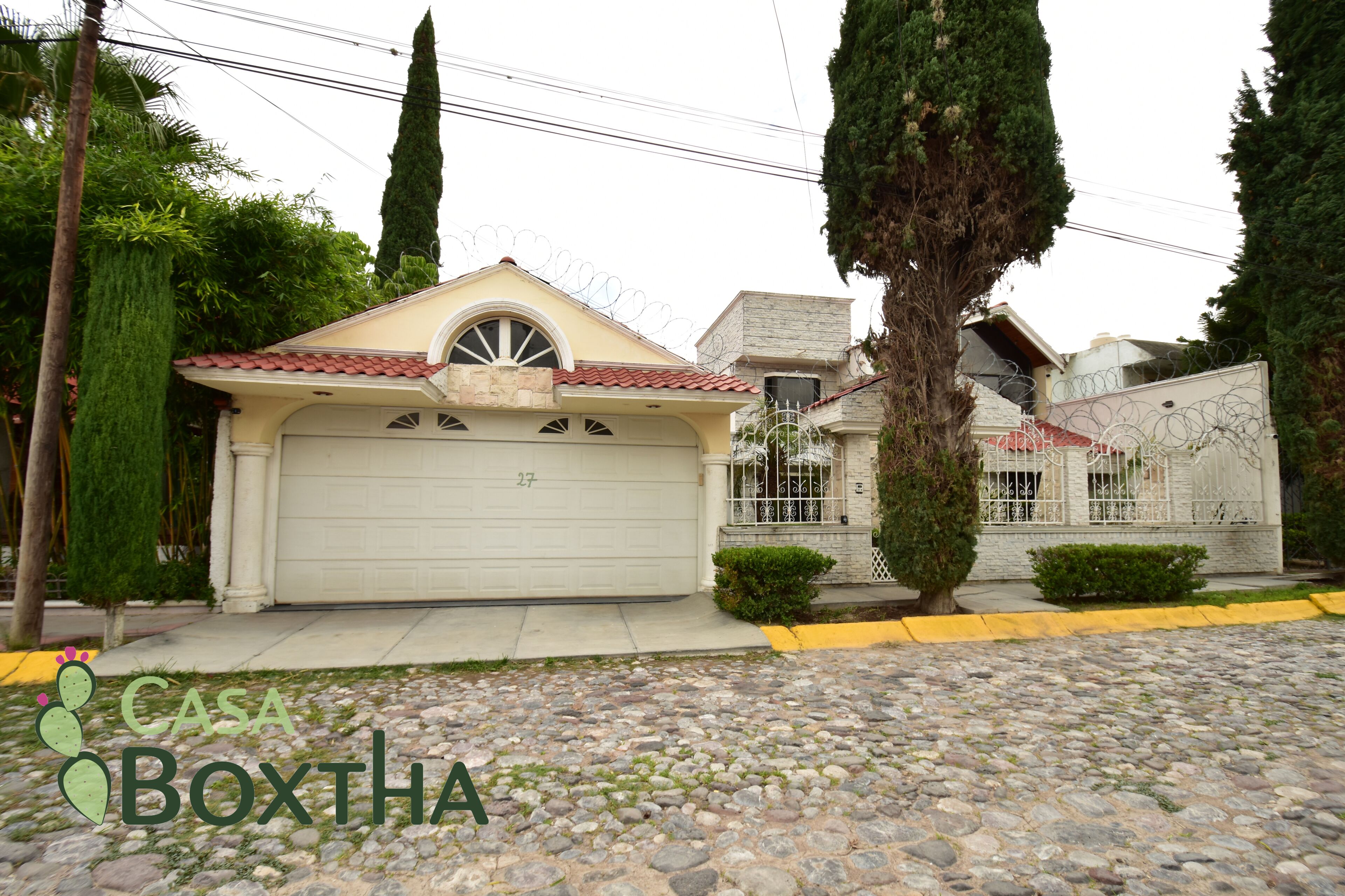 A residential property with a garage, a stone driveway, and a well-maintained lawn.
