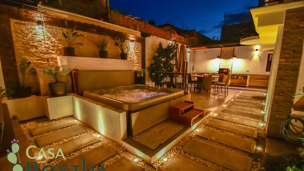 A spa area with a hot tub, stone steps, and potted plants.
