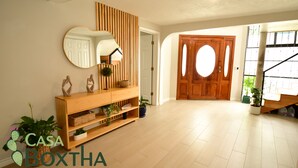 A spacious living area with a wooden console table, a large mirror, and a wooden door with oval windows.