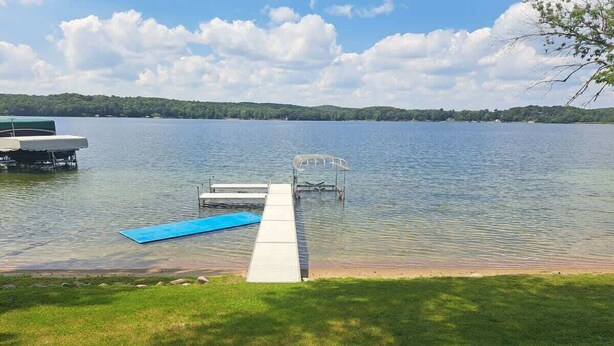 A dock extending into a calm lake with a grassy area in the foreground and a tree-lined shoreline in the background. - Lake Seven, Frazee, MN (Frazee)