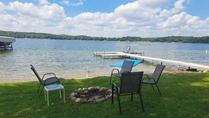 A lakeside deck with chairs, a fire pit, and a dock extending into the water. - Lake Seven, Frazee, MN (Frazee)
