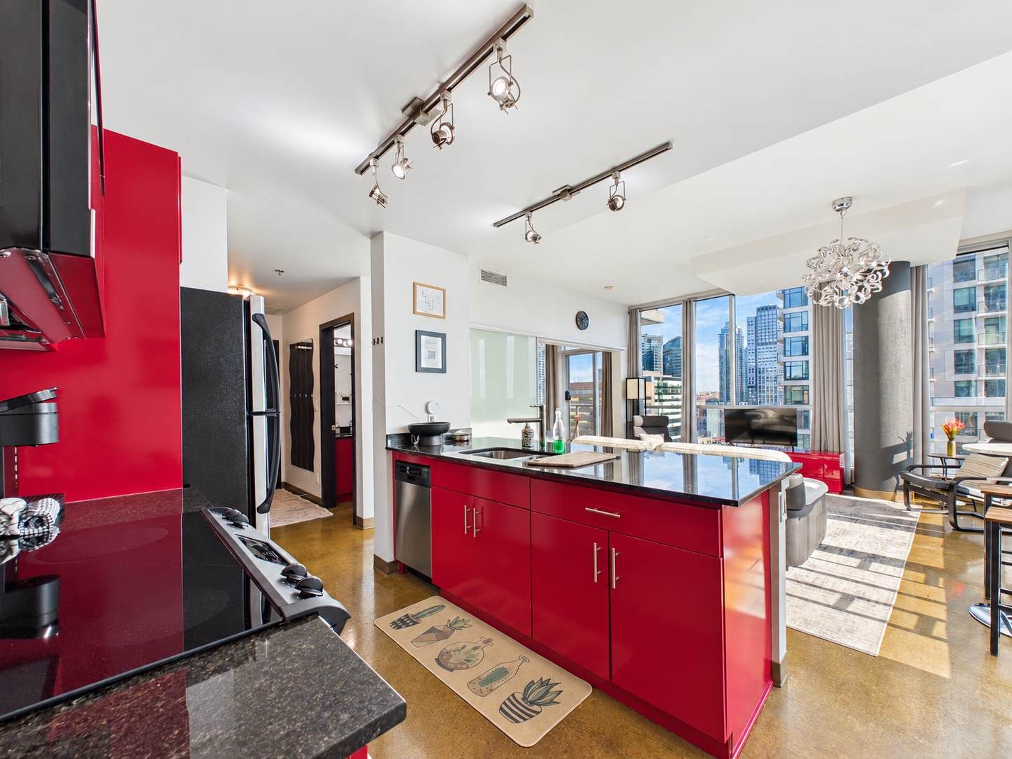 A modern kitchen with red cabinets, a black island, and stainless steel appliances.