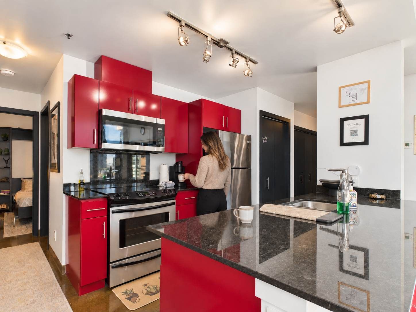 A modern kitchen with red cabinets, stainless steel appliances, and a central island.