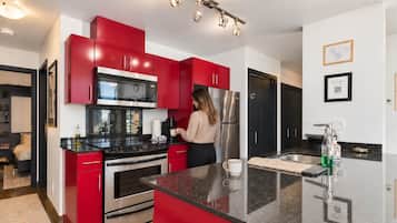 A modern kitchen with red cabinets, stainless steel appliances, and a central island.