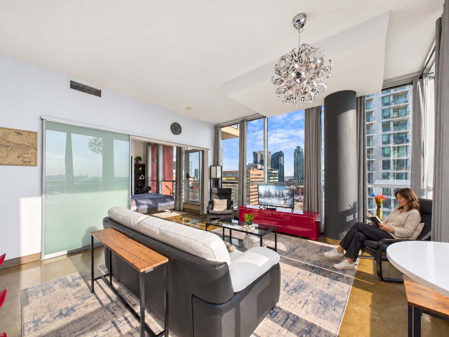 A modern living room with a sofa, a coffee table, and a city view through large windows.