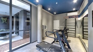 Un gimnasio moderno con cintas de correr, pesas y un amplio ventanal con vistas a un jardín.