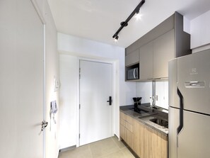 A modern kitchen with stainless steel appliances, wooden cabinets, and a microwave. - Studio With Balcony 100m From Puc-pompeia Puq0208 (São Paulo)