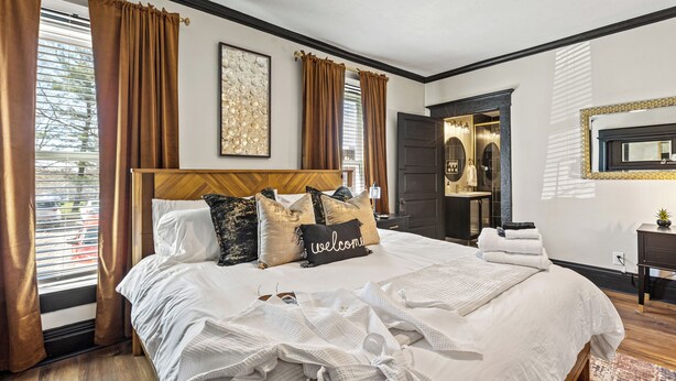 Habitación de hotel con una cama grande, ventilador de techo y vistas al exterior a través de la ventana.