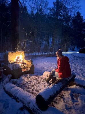 A person sitting by a campfire in a snowy outdoor setting. - Soothing house with AC just north of Williamsport - 2 bedrooms (Trout Run)