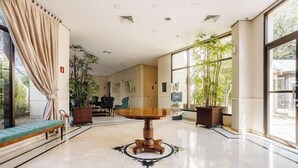 A spacious lobby with a round wooden table, large windows, and potted plants. - Elegant Apt, Near Ibirapuera - Qsa1405 (São Paulo)