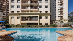 A swimming pool with a tiled deck, surrounded by a multi-story building with balconies. - Elegant Apt, Near Ibirapuera - Qsa1405 (São Paulo)