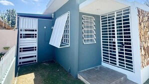 Una casa moderna con facciata blu, un piccolo giardino antistante e un garage con cancello bianco.