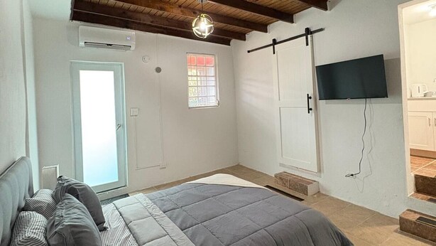 Una camera da letto con un letto, una TV a parete, una finestra e una porta.