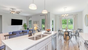 A modern kitchen with a central island, built-in dishwasher, and a dining area with a large window.
