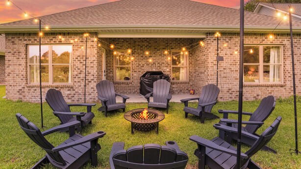 A brick house with a covered patio, outdoor seating, and a fire pit.