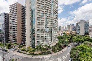 A high-rise building with multiple balconies, surrounded by other buildings and greenery.
