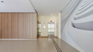 Een modern interieur met een lange gang, twee liften en een patroonwand.