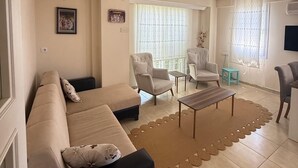 Een woonkamer met een zithoek, twee fauteuils, een salontafel en een bijzettafeltje.