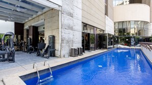 An outdoor swimming pool with gym equipment nearby, surrounded by a modern building with large windows. - Cozy Apartment in Itaim Bibi Spz0610 (São Paulo)