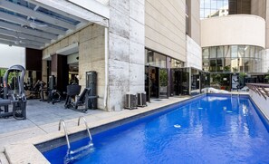 An outdoor swimming pool with gym equipment nearby, surrounded by a modern building with large windows. - Cozy Apartment in Itaim Bibi Spz0610 (São Paulo)