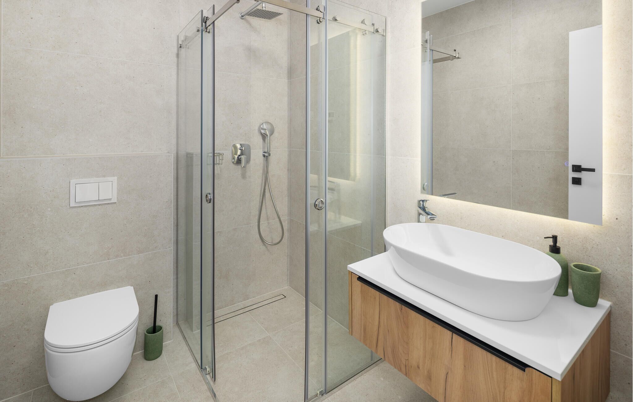 Une salle de bain moderne avec une douche à parois de verre, un lavabo blanc et des toilettes.