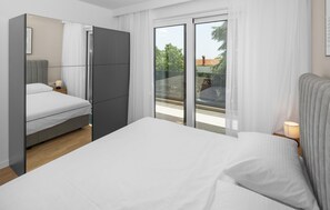 Une chambre d’hôtel moderne dotée d’un grand lit, d’une armoire et d’un balcon offrant une vue sur la ville.