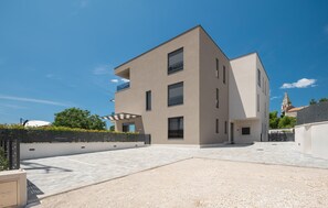Un immeuble moderne à plusieurs étages, doté d’un toit plat, de grandes fenêtres et d’une cour dallée.