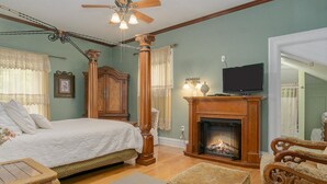 A bedroom with a bed, wooden furniture, a fireplace, and a television. - Lumberman's Suite at Newaygo Bed & Breakfast (Newaygo)