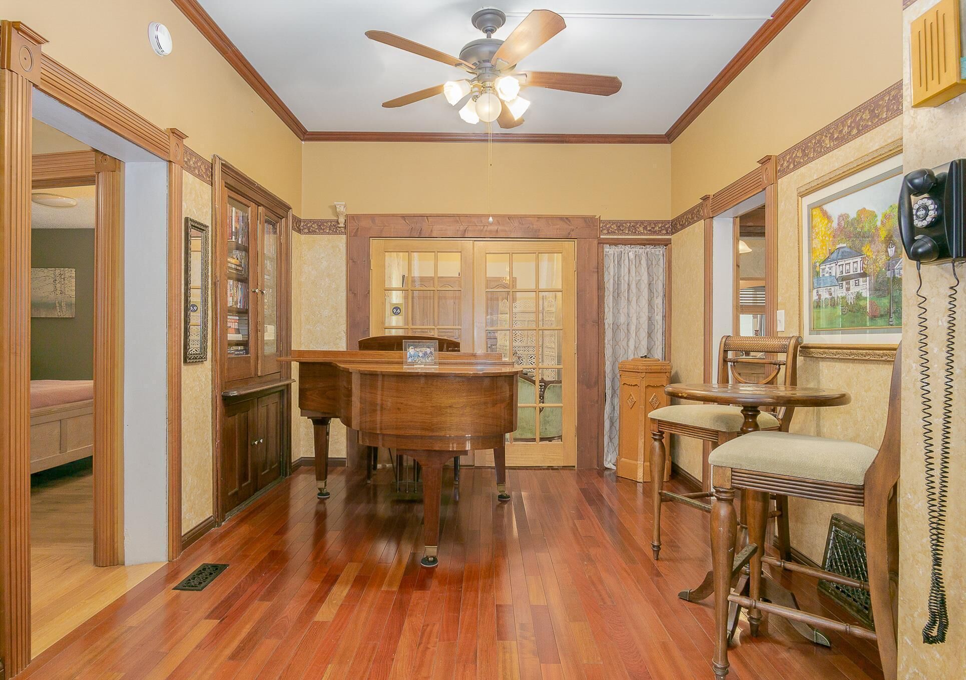 A dining area with a wooden table and chairs, a ceiling fan, and a view of the outside through a door.