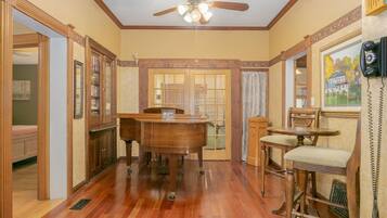 A dining area with a wooden table and chairs, a ceiling fan, and a view of the outside through a door.