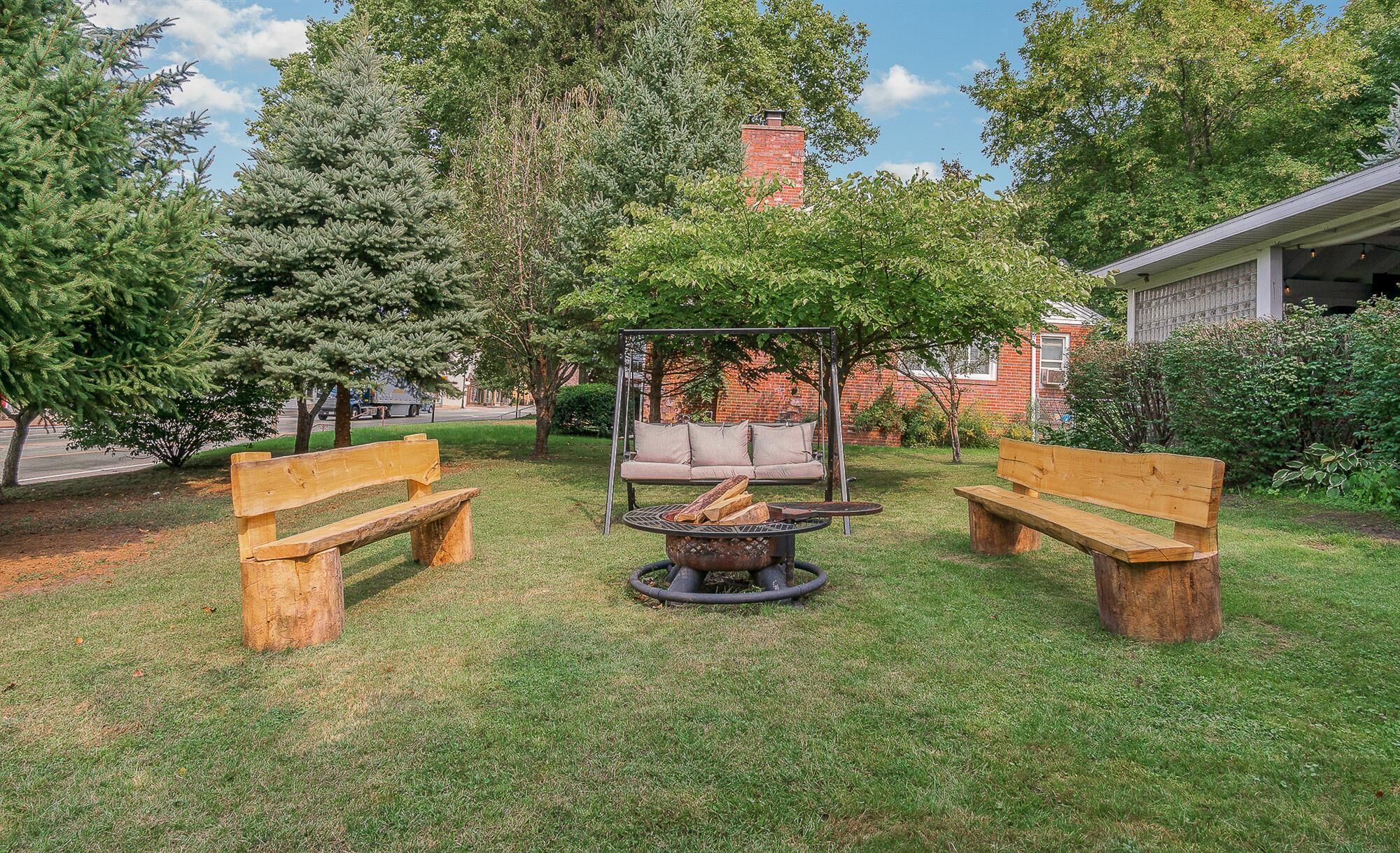 Un patio trasero con dos bancos de madera, un parque infantil y una chimenea.