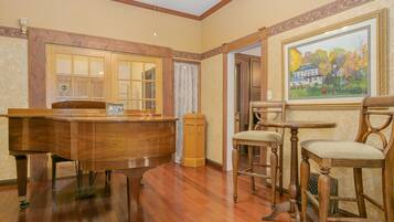 A room with a wooden desk, two chairs, and a painting on the wall.