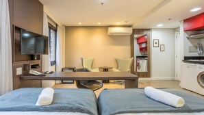 A hotel room with a bed, a desk, a TV, a chair, a table, and a kitchen area. - Modern Studio Just 300m From Moema Metro Sqc0810 (São Paulo)
