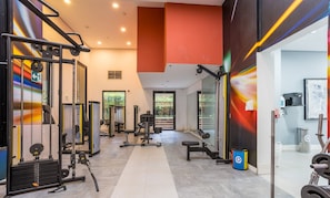 Un gimnasio moderno con diversos equipos de ejercicio, un camino despejado y vistas al exterior a través de un ventanal.