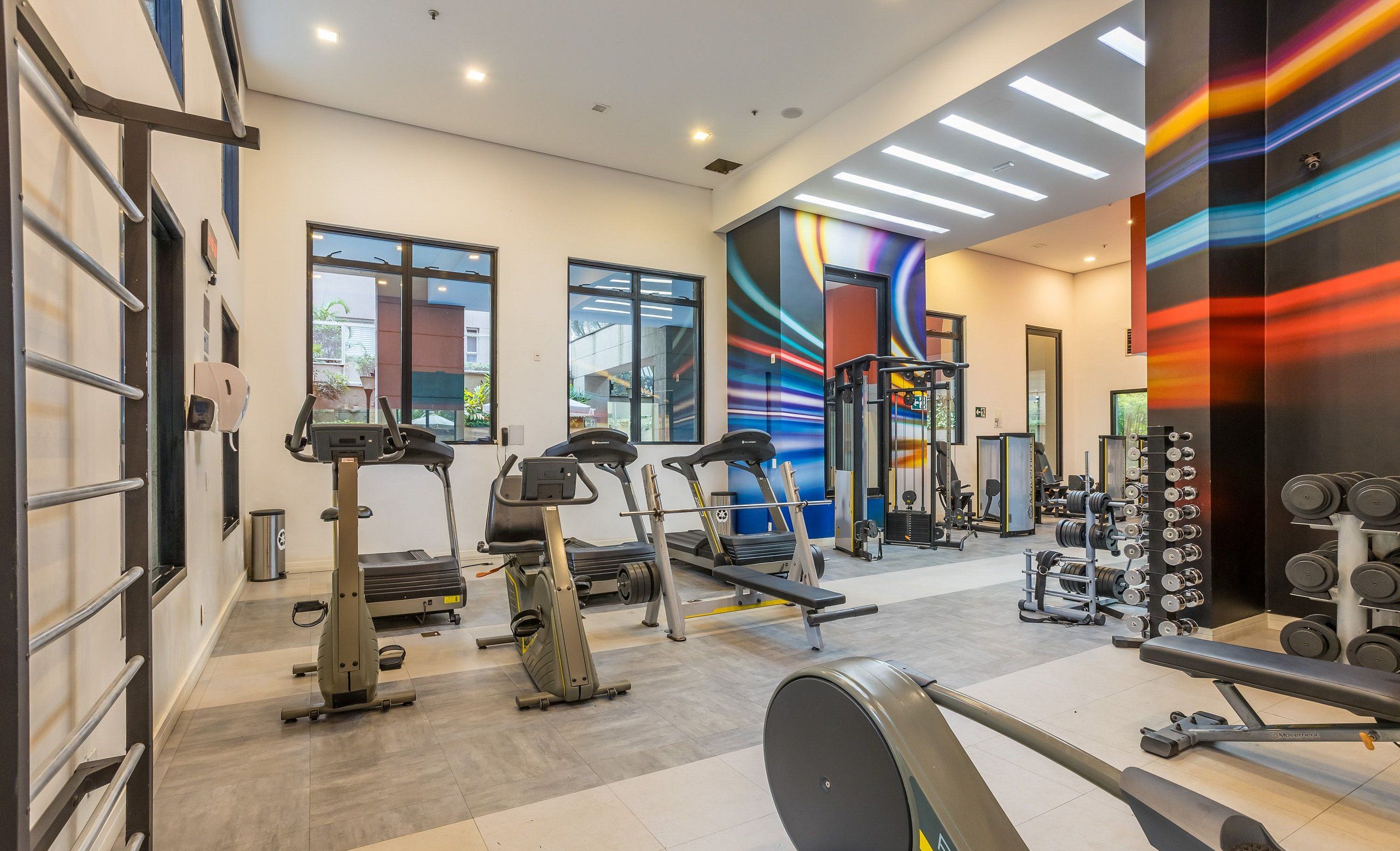 A modern gym with treadmills, elliptical machines, and weightlifting equipment.