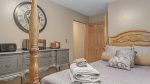 A bedroom with a four-poster bed, a wooden headboard, a clock on the wall, a dresser with a radio, and a door leading to another room. - The Shore Line Room at Newaygo Bed & Breakfast (Newaygo)