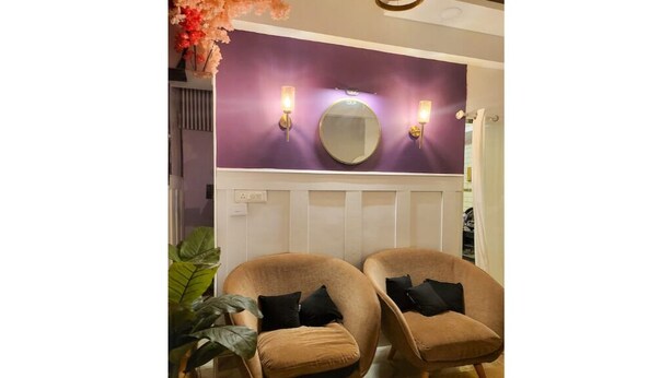 A room with two brown armchairs, a large mirror, and wall sconces. - Amour Bandra: A Cozy Affair at Chapel Rd (Mumbai)