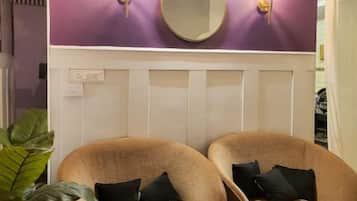 A room with two brown armchairs, a large mirror, and wall sconces.