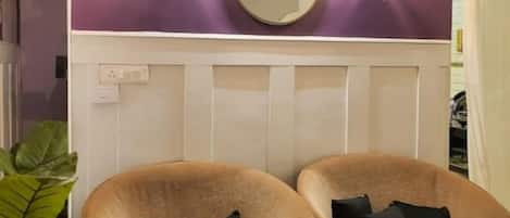 Une pièce avec deux fauteuils marron, un grand miroir et des appliques murales.