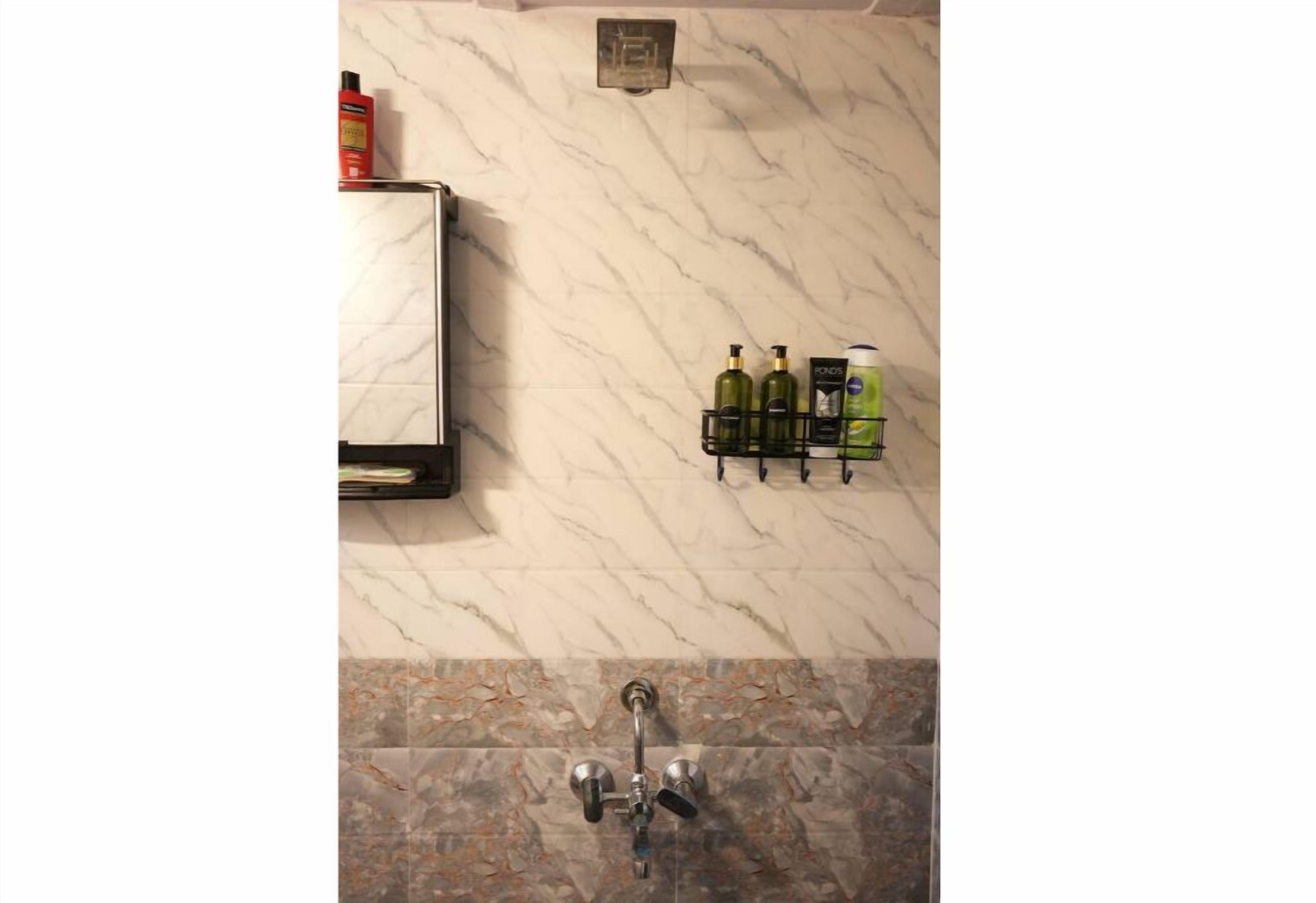 A bathroom with a marble wall, a towel rack with bottles, and a shower with a faucet.