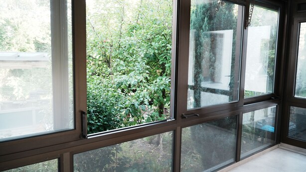 A room with large windows offering a view of a garden. - Central vacation home, near Legoland and city center, with river view - For families (Günzburg)