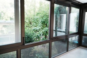 A room with large windows offering a view of a garden.
