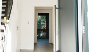 A hallway with a closed door, a staircase, and a view of a garden through a window. - Central vacation home, near Legoland and city center, with river view - For families (Günzburg)