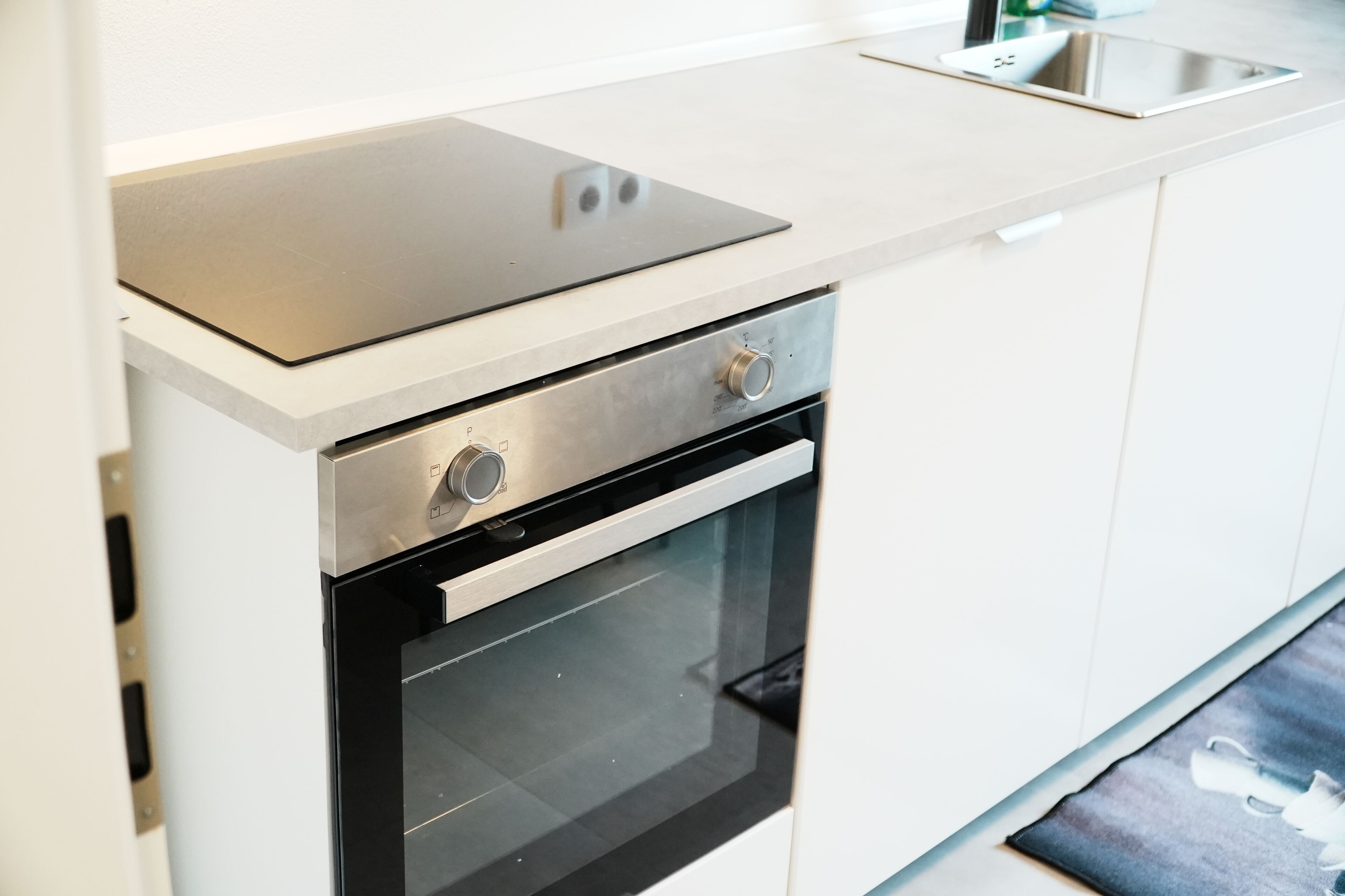 A modern kitchen with a built-in oven, a stainless steel range hood, and a countertop with a sink.
