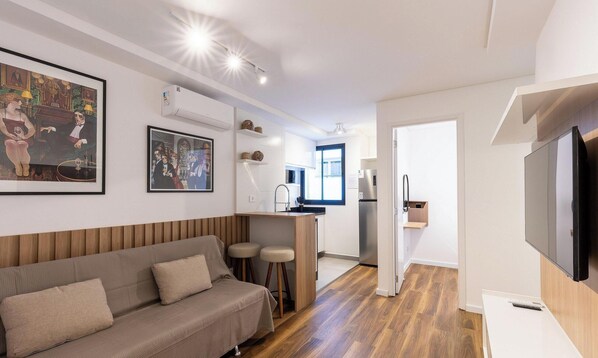 A modern living room with a sofa, a TV, and artwork on the walls.