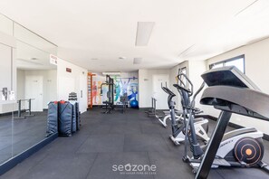 A gym with exercise equipment, a mirrored wall, and a colorful mural.
