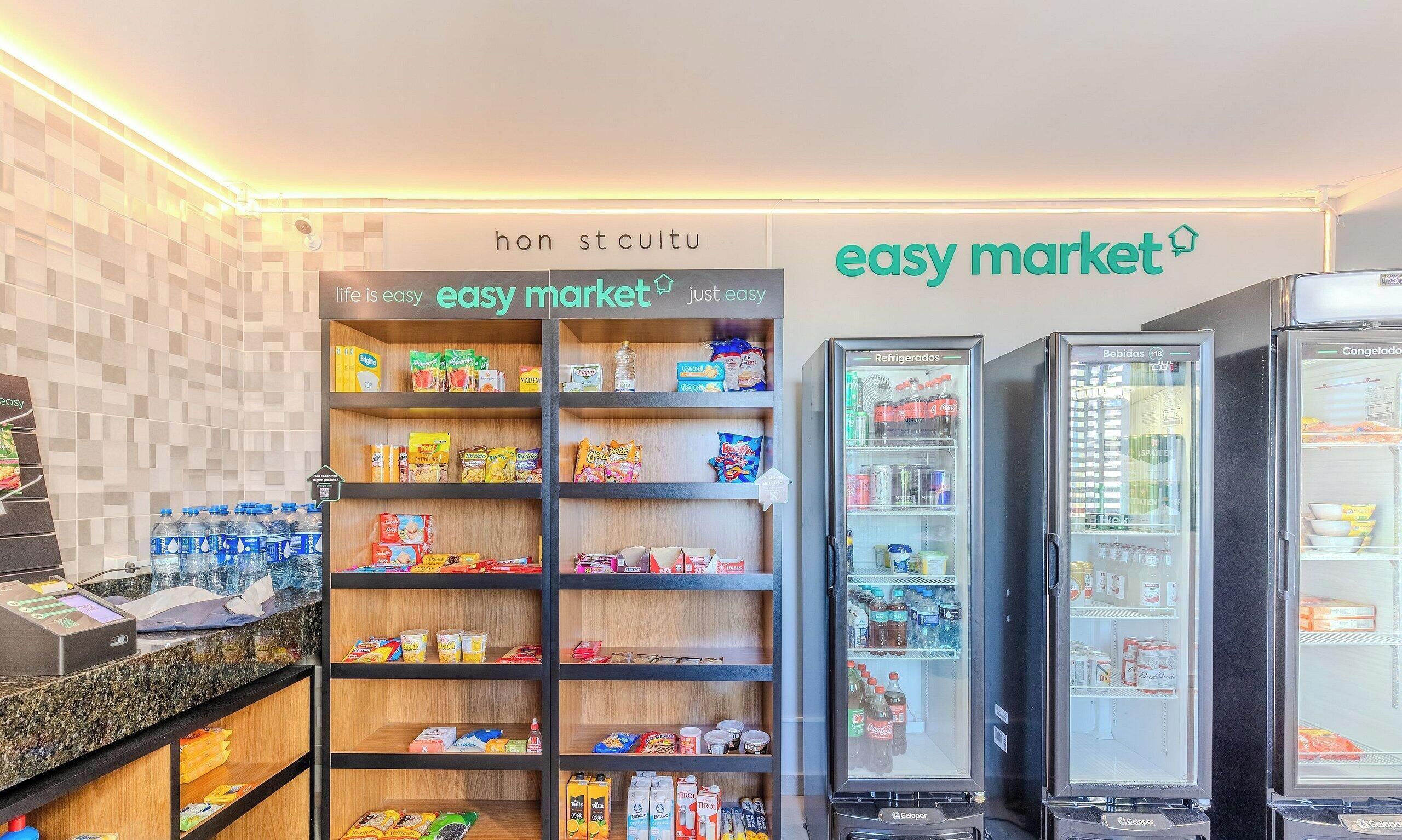 Interior de um supermercado com prateleiras cheias de diversos produtos, um balcão de caixa e expositores refrigerados.