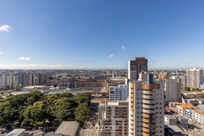 A high-rise building with a modern design, surrounded by other high-rise buildings and a clear sky.