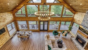 A spacious wooden cabin with a large dining area, a cozy seating area, and a fireplace.