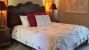 A neatly made bed with a floral bedspread, two bedside lamps, a framed picture on the wall, and a world map. - Gated community 2-bedroom,1 bath attached apartment in Manteca (Manteca)